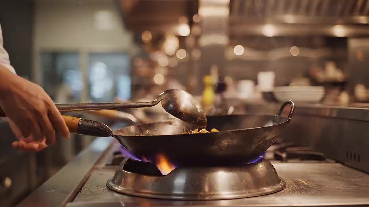 Pad Thai with prawns being tossed in a wok over an open flame in the kitchen
